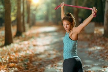 Woman Stretching With Elastic Band Outdoors in The Fall, in Public Park