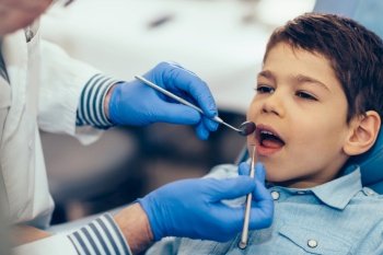 Dentist doing regular dental check-up to little boy.