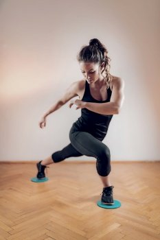 Woman Exercising with Sliding Discs Indoors.. Woman Exercising with Sliding Fitness Discs