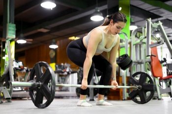 Side view of Athletic woman exercising deadlift in a gym. High quality photo. Side view of Athletic woman exercising deadlift in a gym.
