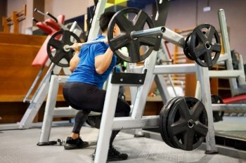Fit man doing squats in a training machine. High quality photo. Fit man doing squats in a training machine.