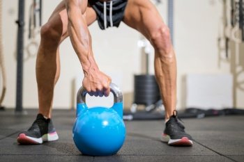Close up of a muscular man lifting heavy kettlebell. High quality photo.. Close up of a muscular man lifting heavy kettlebell