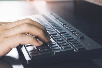 Human hand using computer keyboard on desk