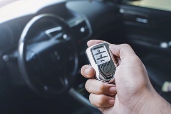 Car keyless entry remote in a hand of the owner car with car interior blurred background