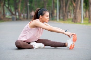 Asian sport woman sit on road and do leg stretching in part or garden.