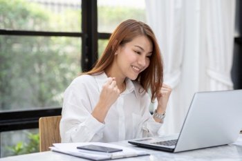 Beautiful Attractive Asian woman celebrating with laptop after success job feeling so happy and cheerful,Business Startup concept 