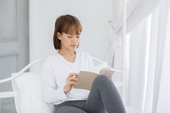 Beautiful Attractive Asian woman sitting on bed in bedroom reading book for learn and education smile and positive thinking feeling so happiness and comfortable,Education Concept