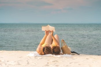 Beauty Attractive Asian woman wearing bikini reading book on the beach smile and relaxation in summer vacations,woman relax on the beach in Tropical island in Thailand,Summer holiday concept