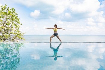 woman practice yoga Warrior one pose to meditation summer vacation on the pool above the beach,Travel in tropical beach Thailand,vacations and relaxation Concept