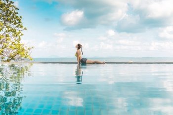 Vacation of Attractive Asian woman practice Cobra Pose on the pool above the beach in the morning with beautiful sea in Tropical island,Feeling comfortable and relax in holiday,Vacations Concept