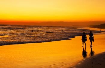 People walking on the ocean beach at sunset.  Bali island, Indonesia