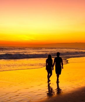 Couple walking on a tropical beach at romantic sunset. Bali island, Indonesia