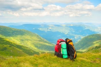 Two colorful hikers backpacks on green slope, scenic Carpathian mountains landscape in background, Ukraine