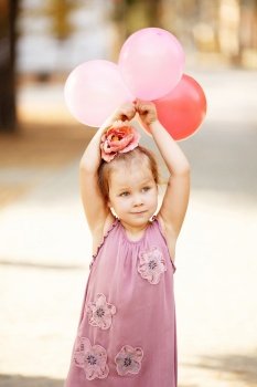 Portrait of laughing and playing little girl holding colorful balloons. Positive emotions. Happy child.