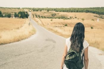 Woman with backpack walking on the road