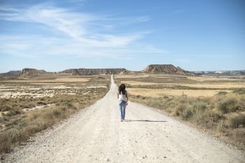 Woman with jeans walking on wild west dirt road
