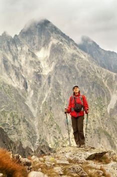 Happy woman with backpack standing on a rocky mountain background. Tatra Mountains, Slovakia, Europe. Hiking woman happy to be in the mountains