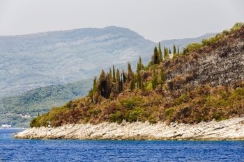 The view from the sea to the rocky beach with a variety of trees