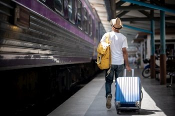Traveler walking and waits train at train station for travel in summer. Travel concept.
