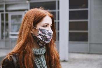 young woman wearing homemade everyday cloth face mask outdoors in city, new normal covid-19 corona virus pandemic or air pollution concept, real people lifestyle in winter. young woman wearing homemade everyday cloth face mask outdoors in city