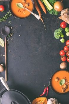Food frame. Bowls of homemade tomato soup and ingredients on rustic background, top view, space for text
