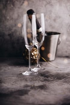Champagne bottle in bucket with ice, glasses and Christmas decorations on grey stone background. Champagne bottle in bucket with ice, glasses and Christmas decorations