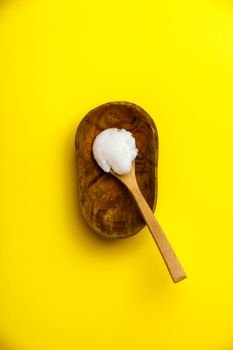 Spoon with coconut oil, on yellow background flat lay. Spoon with coconut oil on yellow background