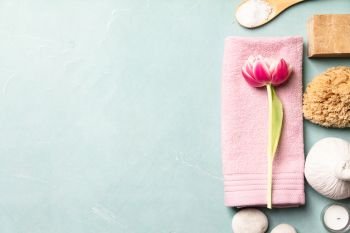 Flat lay of spa treatment set with pink flowers on blue background