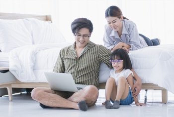 A warm family spending time together at home in holiday. The little girl is studying online by using laptop.