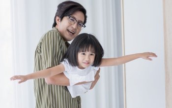 Asian father and daughter playing together at home in holiday