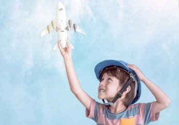 A caucasian little boy is playing model of airplane with background of blue sky