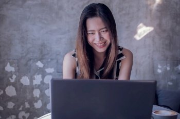 30s asian beautiful woman is using notebook for working while drinking coffee