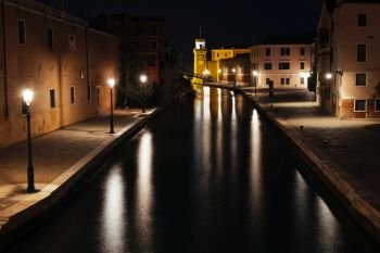 Venice canal with historical buildings and gondolas at night. Italy.