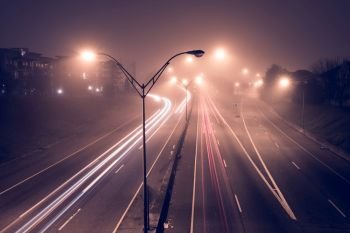 Highway at foggy night with bright trails of light from incoming and outgoing traffic. Transportation, traffic, urbanism and infrastructure concepts.. Highway at foggy night with bright trails of light from incoming and outgoing traffic.