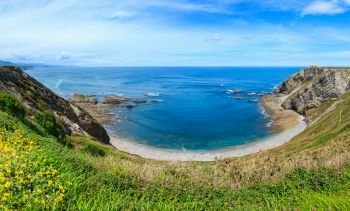 Summer blossoming Cape Vidio coastline landscape with sandy beach and lighthouse (Asturian coast, Cudillero, Spain).
