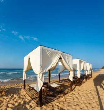 Beach tents canopies on morning paradise white sandy beach. The most beautiful sea sandy beach of Apulia, Italy.