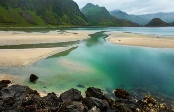 Lofoten fjords and lakes cloudy landscape with sandy beach, lough, and mountains (Norway). Summer polar day night view.