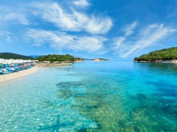Beautiful Ionian Sea with clear turquoise water and morning summer coast view from beach, Ksamil, Albania. People unrecognizable.
