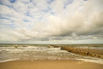 lonesome beach of the Baltic Sea with cloudy sky and surf
