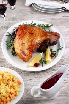 Baked turkey thigh, on the table with cranberry sauce and bulgur pilaf
