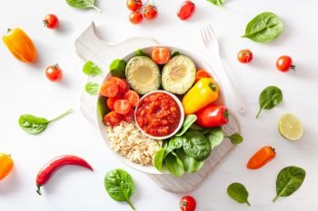 vegan buddha bowl. healthy lunch bowl with avocado, tomato, bell peppers, quinoa and salsa