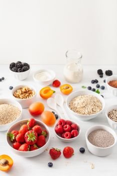 variaty of raw cereals, fruits and nuts for breakfast. Oatmeal flakes and steel cut, barley, walnut, chia, apricot, strawberry. Healthy ingredients