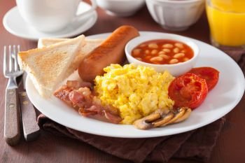 full english breakfast with scrambled eggs, bacon, sausage, beans, tomato