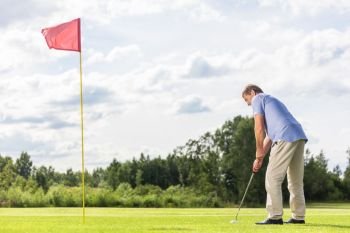 Senior man playing golf on a golf course. Sport and leisure activity.. Senior man playing golf.