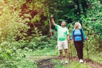 Elderly couple admiring nature and walking in the woods. Sportive lifestyle.. Elderly couple admiring nature and walking