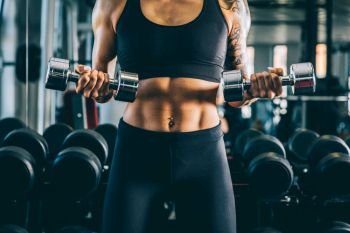 Woman standing with dumbbells in the gym. Athletic body. 