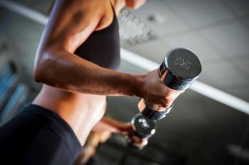 Fit woman exercising with dumbbells at the gym. Body training, weightlifting workout. Healthy lifestyle.. Fit woman exercising with dumbbells at the gym.