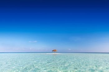Tropical sandbank island with sunshade umbrella. Indian Ocean, Maldives. Blue clear sky. Tropical sandbank island with sunshade umbrella. Indian Ocean, Maldives.
