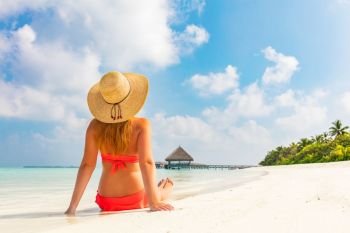 Beautiful young woman in sunhat sitting relaxed on sand, tropical beach in Maldives. Beautiful young woman in sunhat sitting relaxed on tropical beach in Maldives