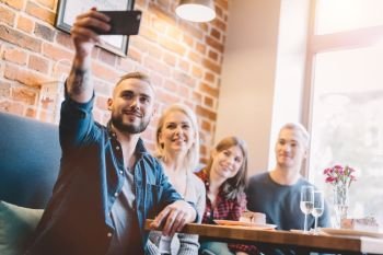 Group of people taking a selfie together in a restaurant. Modern days gadgets. Group picture.. Group of people taking a selfie together in a restaurant.